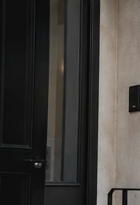 Illustrative residential entrance with a dark door and warm stone finish